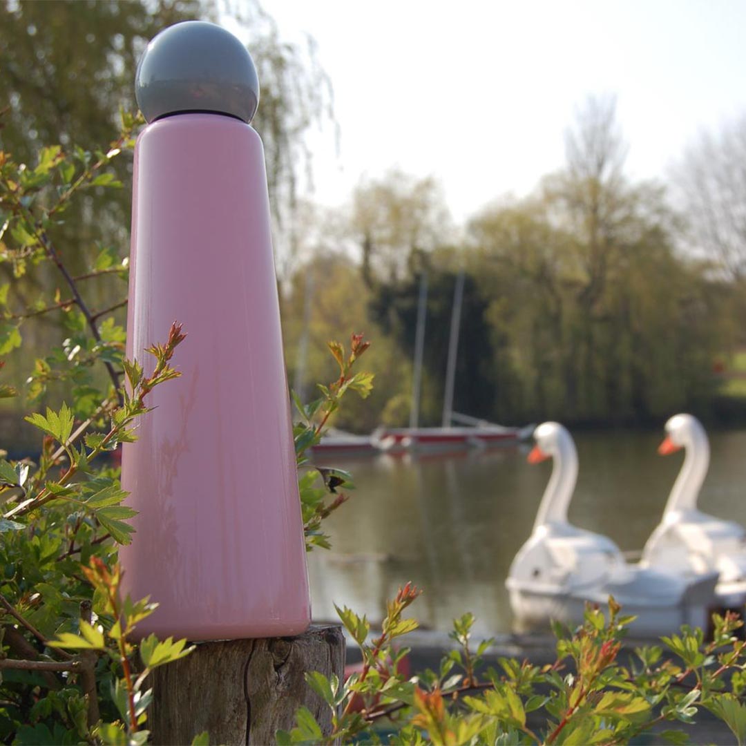 750ml Skittle Water Bottle on the bank of a boating lake with swan pedalo boats in the background.